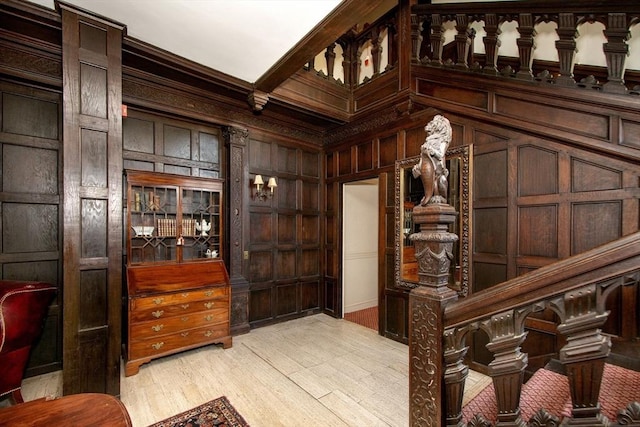 interior space with light hardwood / wood-style flooring, beamed ceiling, wooden walls, and ornamental molding