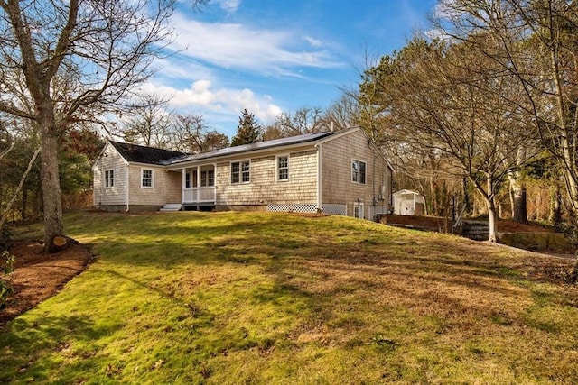 rear view of property with a lawn and a storage unit