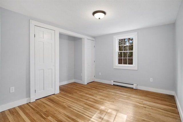 unfurnished bedroom featuring light wood-type flooring and a baseboard heating unit