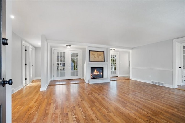 unfurnished living room featuring french doors and light hardwood / wood-style flooring