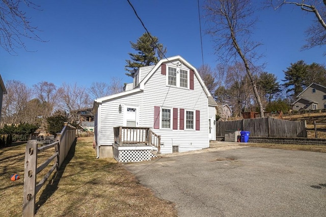 back of property with a gambrel roof, driveway, and fence