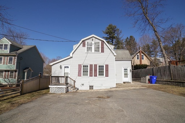 back of property with fence and a gambrel roof