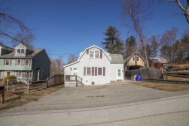 view of front of home featuring fence, a gambrel roof, and driveway