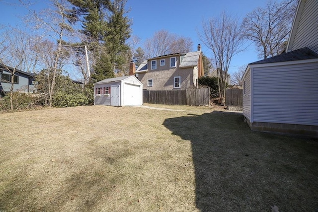 view of yard featuring an outbuilding, a detached garage, a storage shed, and fence