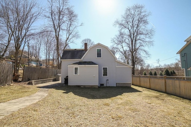 rear view of house with a shingled roof, fence, a gambrel roof, a lawn, and a chimney