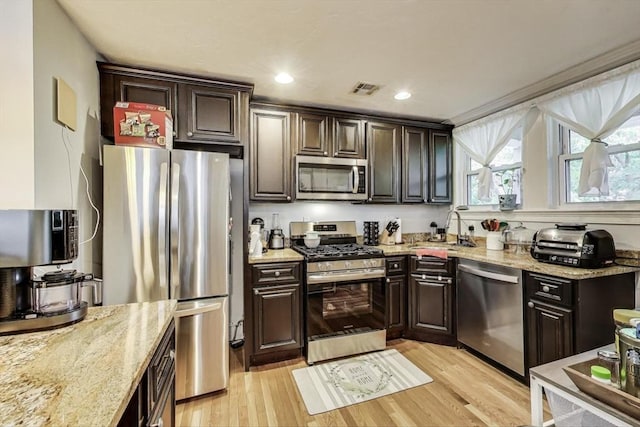 15 Ronan St Unit 3, Boston, MA 02125 - kitchen featuring appliances with stainless steel finishes, a sink, light wood-style floors, light stone counters, and dark brown cabinetry