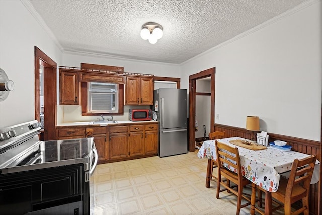 12 Leonard St, Somerville, MA 02144 - kitchen featuring stainless steel appliances, wainscoting, brown cabinetry, a textured ceiling, and ornamental molding