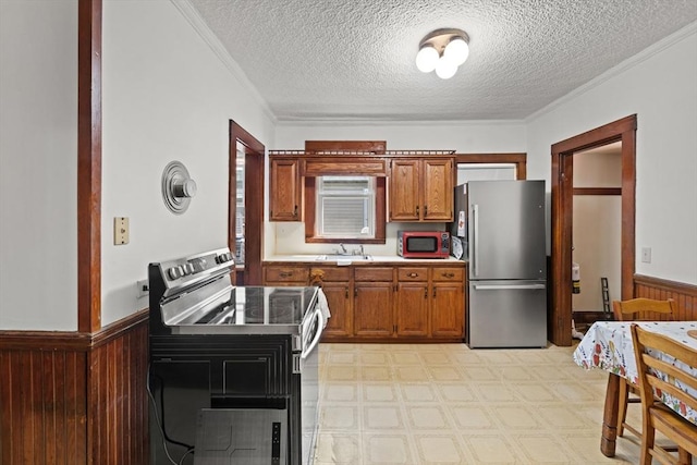 12 Leonard St, Somerville, MA 02144 - kitchen featuring appliances with stainless steel finishes, a wainscoted wall, ornamental molding, a textured ceiling, and brown cabinetry