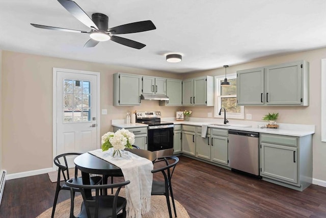 kitchen with baseboards, dark wood finished floors, appliances with stainless steel finishes, light countertops, and under cabinet range hood