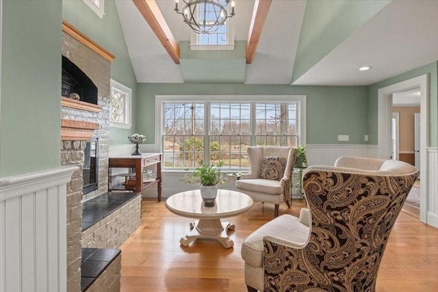 279 Norfolk St, Holliston, MA 01746 - living area with a glass covered fireplace, wainscoting, wood finished floors, lofted ceiling, and a chandelier