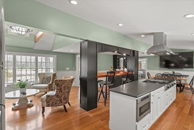 279 Norfolk St, Holliston, MA 01746 - kitchen with stainless steel appliances, dark countertops, white cabinets, island exhaust hood, and light wood-style flooring