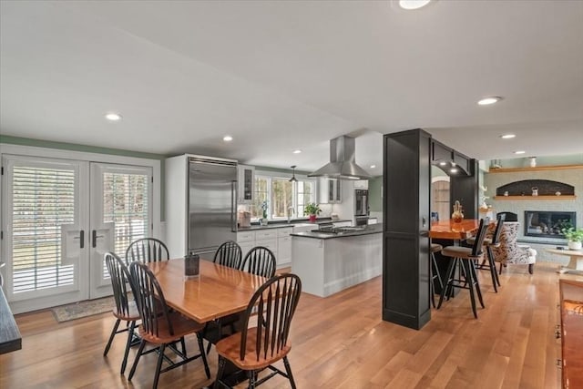 279 Norfolk St, Holliston, MA 01746 - dining space featuring light wood-style flooring, french doors, recessed lighting, and a large fireplace
