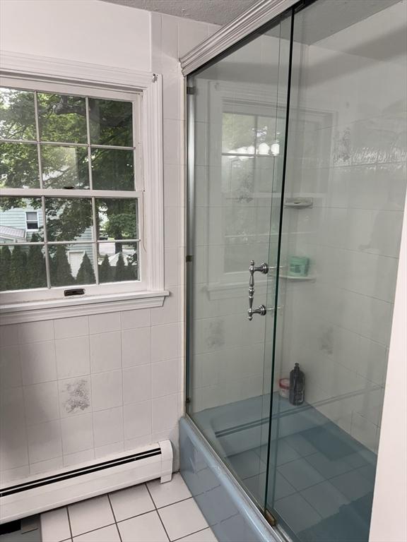 251 Waltham St, Newton, MA 02465 - bathroom with tile patterned floors, a baseboard heating unit, healthy amount of natural light, and bath / shower combo with glass door