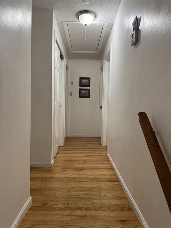 251 Waltham St, Newton, MA 02465 - hall with attic access, light wood finished floors, baseboards, a textured ceiling, and an upstairs landing