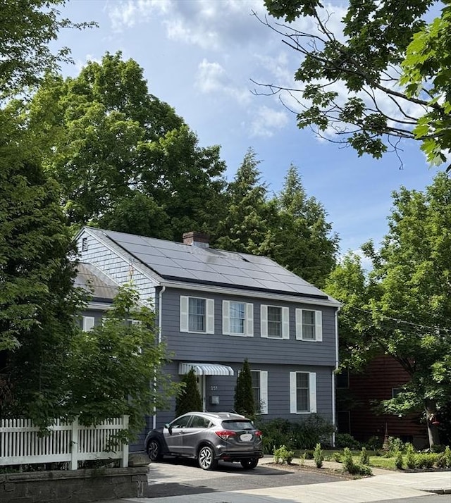 251 Waltham St, Newton, MA 02465 - colonial-style house featuring roof mounted solar panels and a chimney