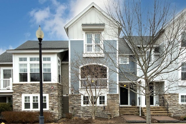 view of front of house featuring stone siding, a shingled roof, and board and batten siding