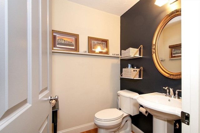 half bath with a sink, toilet, and baseboards