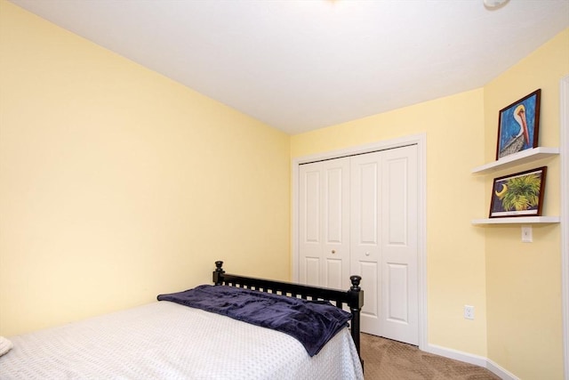 bedroom with baseboards, a closet, and light colored carpet