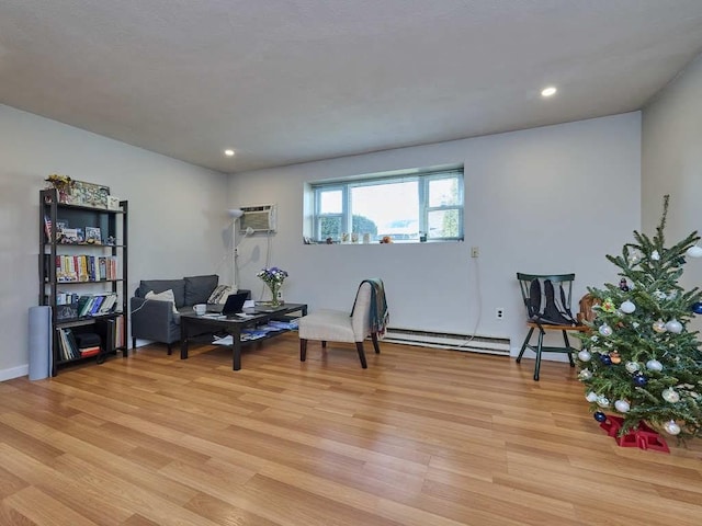 living area featuring light hardwood / wood-style floors, a wall mounted air conditioner, and a baseboard heating unit