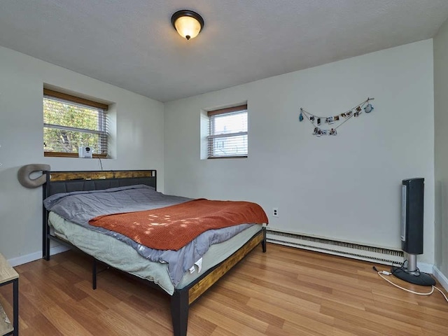 bedroom featuring hardwood / wood-style floors and a baseboard radiator