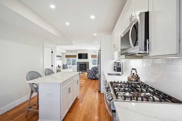 10 Berkley Rd Unit C, Hull, MA 02045 - kitchen with stainless steel appliances, a sink, open floor plan, a kitchen breakfast bar, and white cabinetry