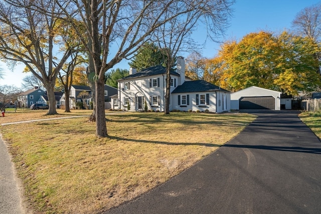 view of front of property with a garage, an outdoor structure, and a front yard