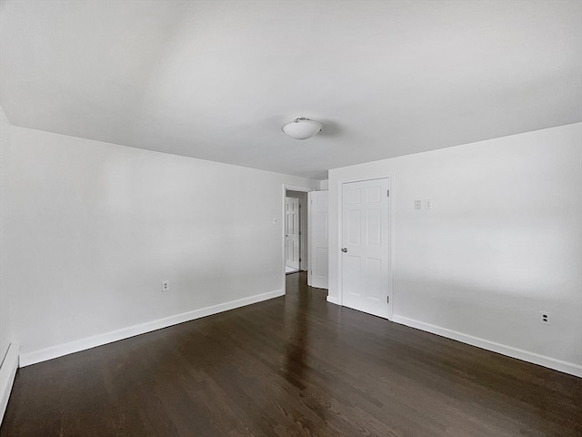 unfurnished room with dark wood-type flooring and a baseboard heating unit