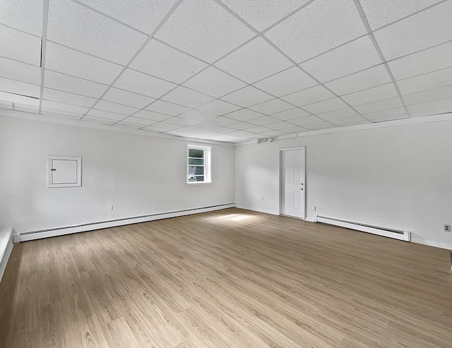 interior space with a baseboard heating unit, light hardwood / wood-style flooring, and a paneled ceiling