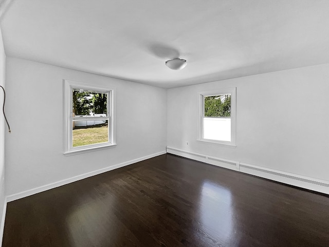 empty room with dark hardwood / wood-style flooring and a baseboard radiator