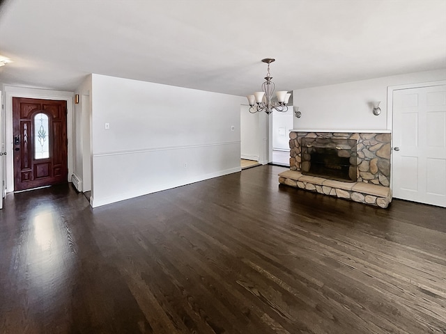 unfurnished living room with dark hardwood / wood-style flooring, a fireplace, an inviting chandelier, and a baseboard heating unit