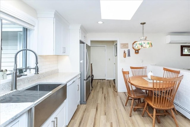 15 Trask Rd, Peabody, MA 01960 - kitchen featuring a wall mounted AC, freestanding refrigerator, white dishwasher, a skylight, and white cabinets