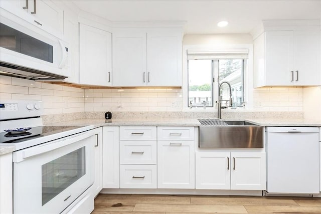 15 Trask Rd, Peabody, MA 01960 - kitchen with white appliances, white cabinets, light stone countertops, tasteful backsplash, and light wood-style flooring