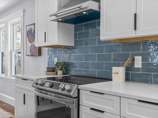 kitchen featuring stainless steel electric range, white cabinets, tasteful backsplash, and ventilation hood