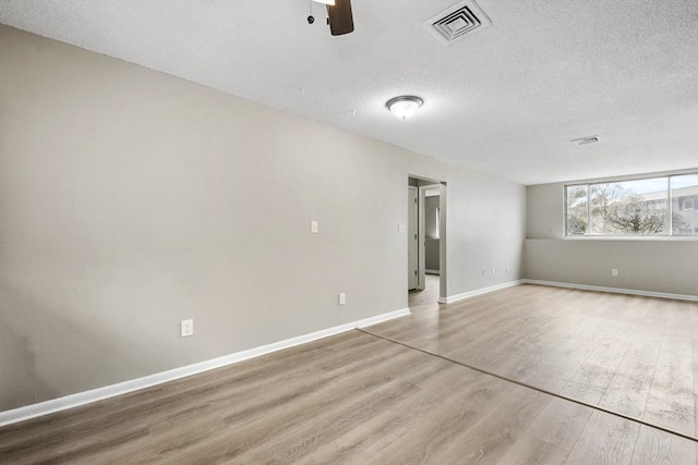 unfurnished room featuring baseboards, a textured ceiling, visible vents, a ceiling fan, and wood finished floors