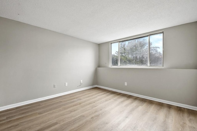 spare room featuring baseboards, a textured ceiling, and wood finished floors