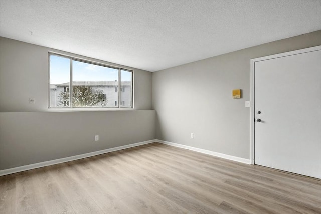 spare room with baseboards, a textured ceiling, and wood finished floors