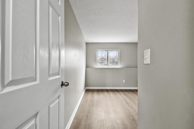 spare room featuring wood finished floors, baseboards, and a textured ceiling