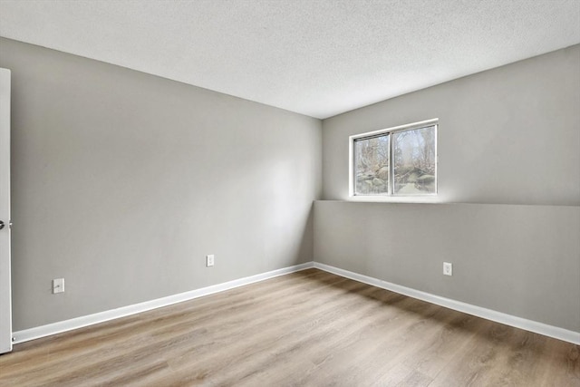empty room featuring baseboards, wood finished floors, and a textured ceiling