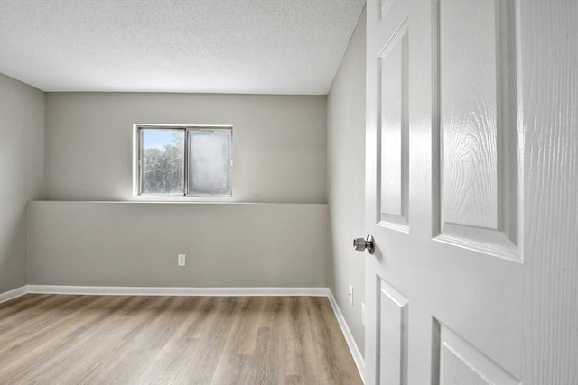 spare room with baseboards, a textured ceiling, and wood finished floors