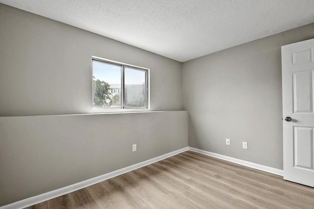 spare room with a textured ceiling, baseboards, and wood finished floors
