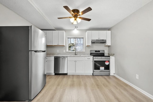 kitchen featuring white cabinetry, under cabinet range hood, a sink, a ceiling fan, and appliances with stainless steel finishes