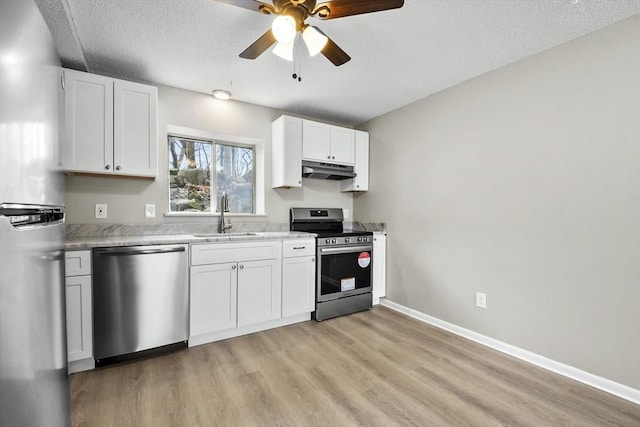 kitchen featuring light countertops, a sink, a ceiling fan, under cabinet range hood, and stainless steel appliances