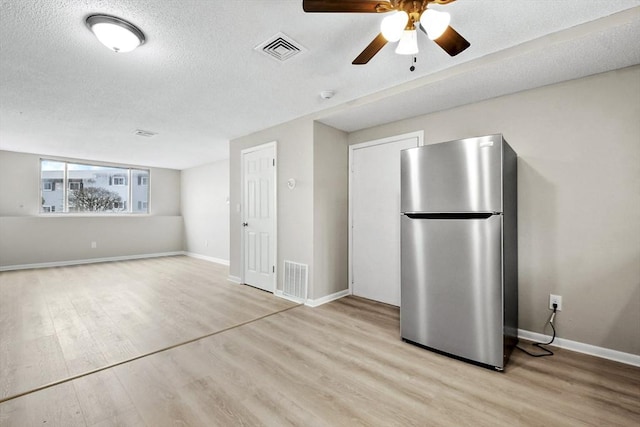 interior space with visible vents, light wood-style flooring, and freestanding refrigerator