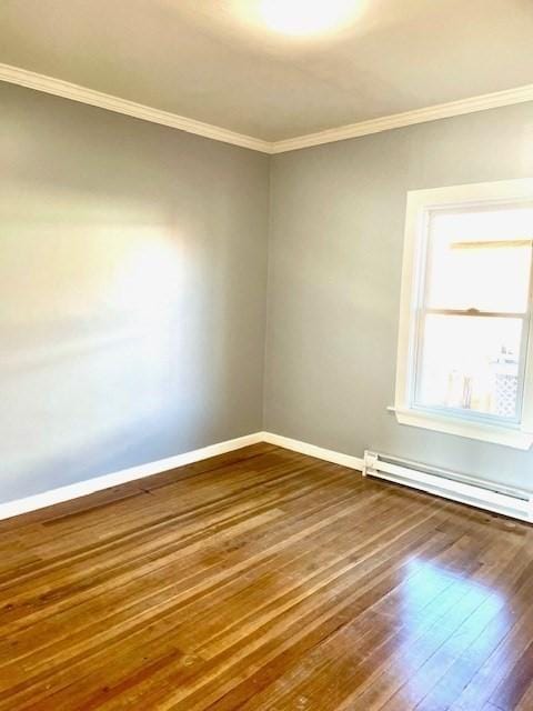 empty room with ornamental molding, hardwood / wood-style flooring, and a baseboard heating unit