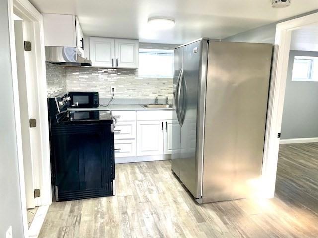 kitchen with white cabinets, range, tasteful backsplash, sink, and stainless steel fridge