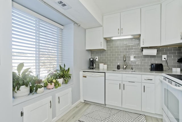 kitchen with white appliances, a sink, visible vents, white cabinets, and tasteful backsplash