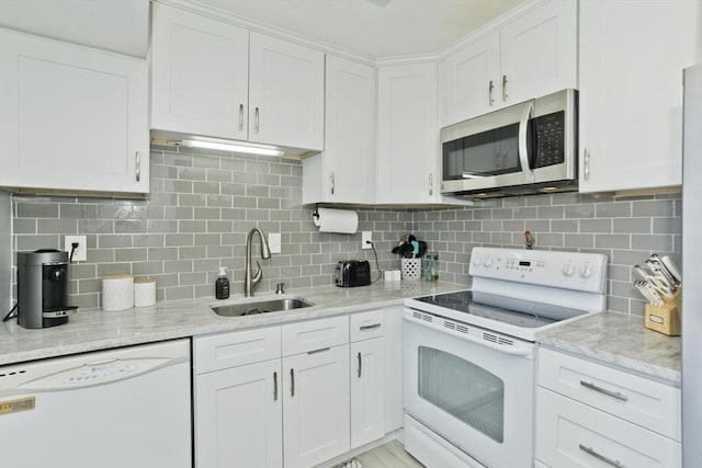 kitchen with white appliances, white cabinetry, a sink, and light stone countertops