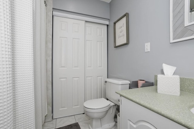 bathroom featuring toilet, curtained shower, tile patterned flooring, and vanity