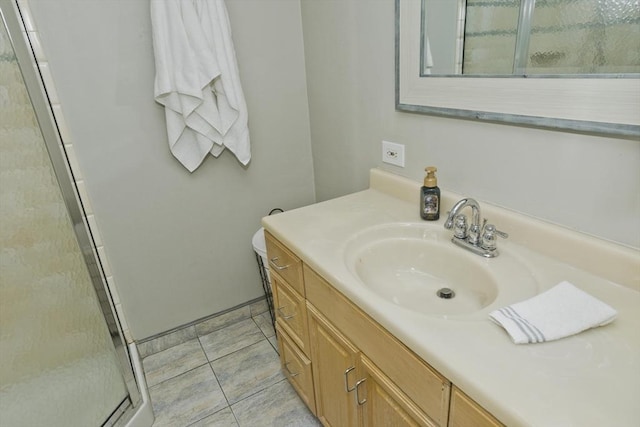 bathroom with a shower with door, vanity, and tile patterned floors