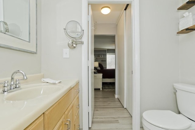 ensuite bathroom with vanity, wood finished floors, ensuite bath, and toilet